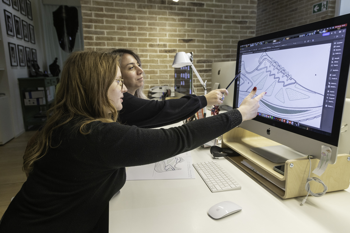Due membri Sport Commerce che si confrontano sul design di una scarpa