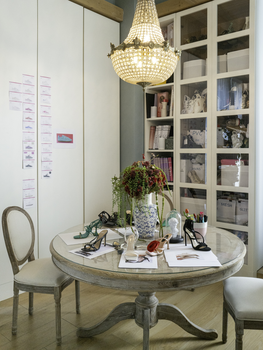 Un'elegante stanza dell'azienda sport commerce con modelli di scarpe su un tavolo di legno bianco e un lampadario dorato che illumina l'ambiente